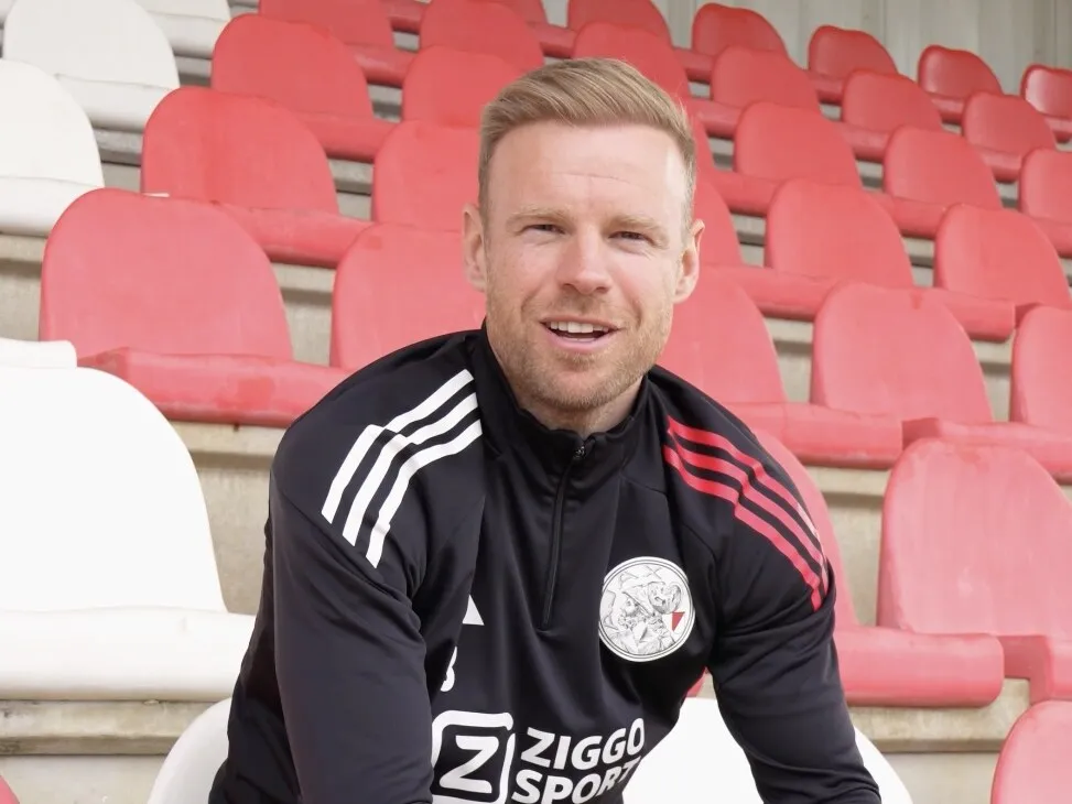 Voetballer in trainingspak tijdens een interview op de tribune