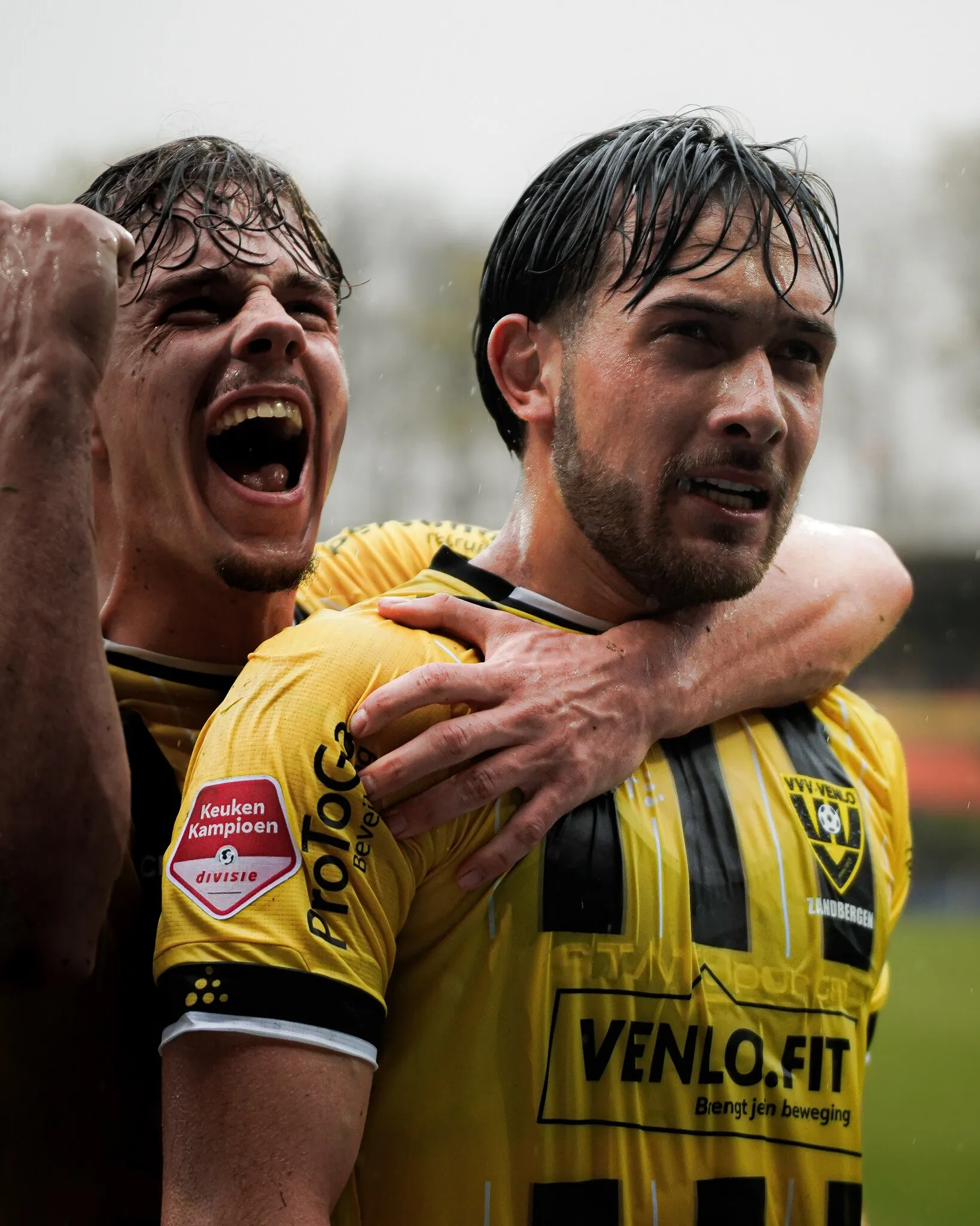 Twee spelers vieren een doelpunt met de arm om elkaars schouder